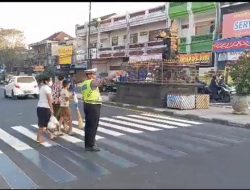 Personil Lalu Lintas Polres Tabanan Membantu Seberangkan PJK dan Atur Lalin Di Hari Minggu